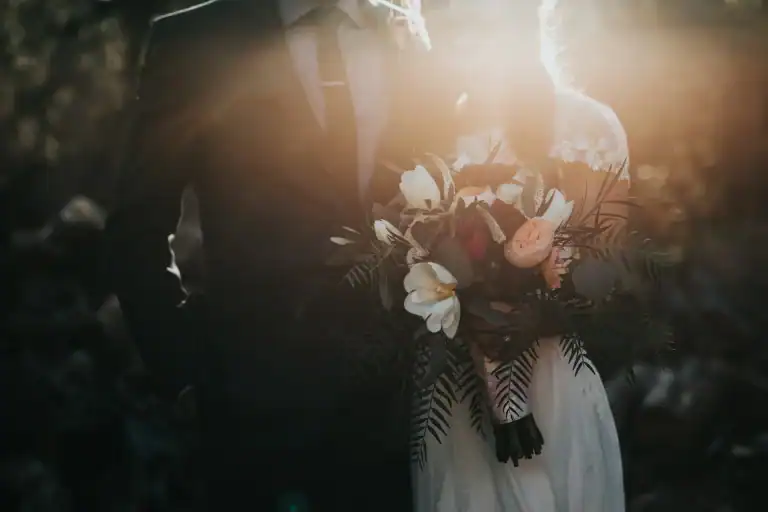 couple just married, woman holing bouquet of flowers. Sun setting